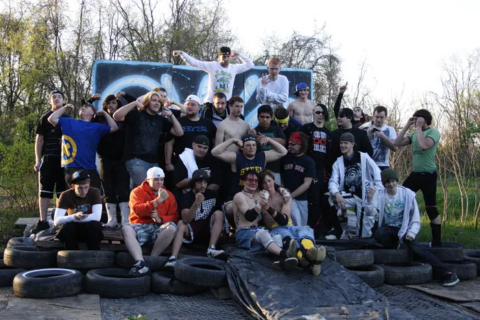 Crew photo in front of a graffiti wall beside a stack of tires