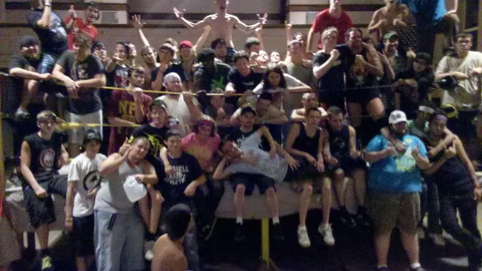 Crew hanging off the ropes and turnbuckles of a backyard ring
