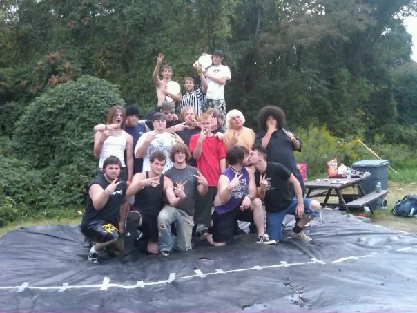 Crew gathered on a tarp mat in a wooded backyard